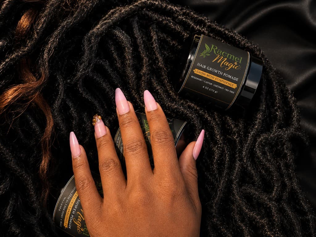 Hand holding Racmel Magic Hair Growth Pomade over locs and satin