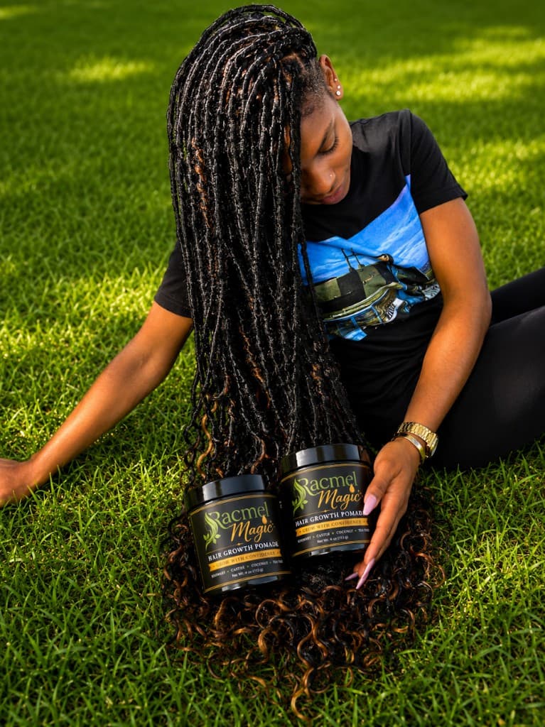 Customer with long locs holding Racmel Magic Hair Growth Pomade outdoors